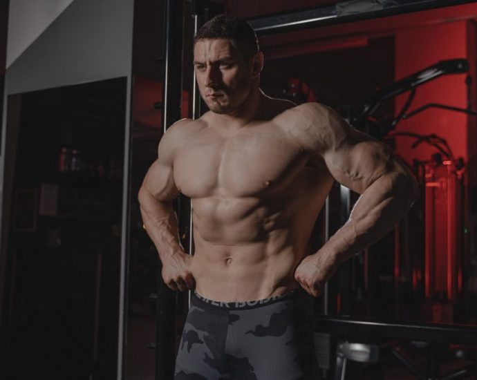 Shirtless bodybuilder flexing muscles under dramatic gym lighting. Fitness and strength.