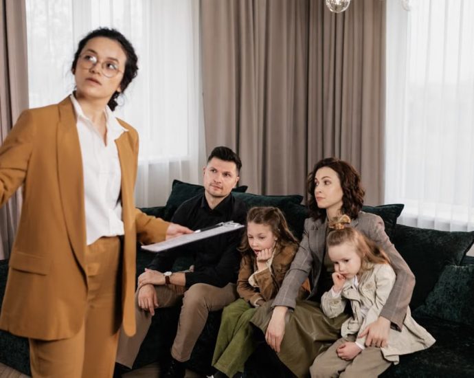 A real estate agent presenting property options to a family in a living room setting.