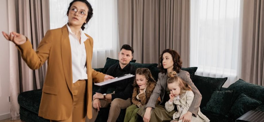 A real estate agent presenting property options to a family in a living room setting.