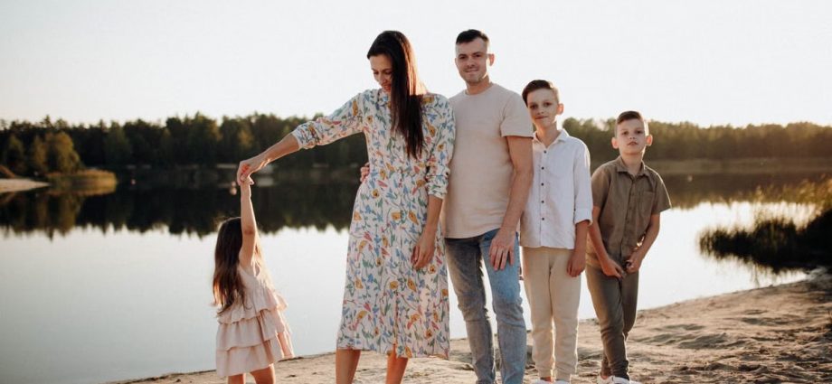 A family of five enjoys a serene lakeside vacation at sunset, capturing precious moments together.